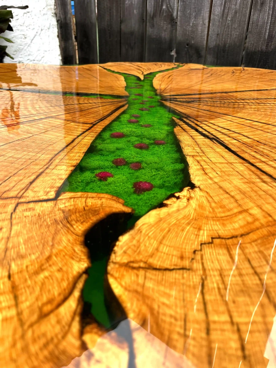 ogromny stół jadalniany z plastra dębowego z żywicą epoksydową mchem oraz kwiatami polnymi na drewnianych nogach przybliżenie na żywicę