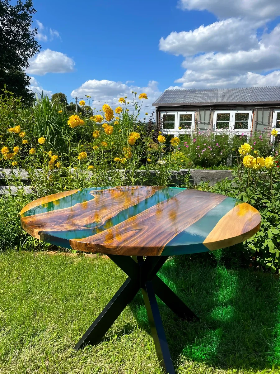 okrągły stół jadalniany z desek orzecha włoskiego w połączeniu z turkusową żywicą epoksydową na metalowych nogach zabezpieczony lakierem w połysku
