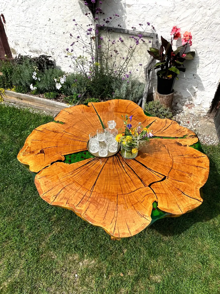 ogromny stół jadalniany z plastra dębowego z żywicą epoksydową mchem oraz kwiatami polnymi na drewnianych nogach z zastawą