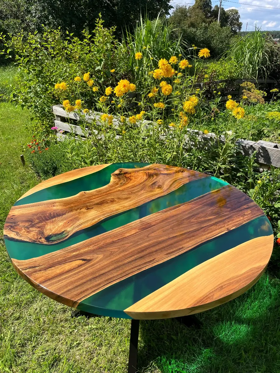 okrągły stół jadalniany z desek orzecha włoskiego w połączeniu z turkusową żywicą epoksydową na metalowych nogach zabezpieczony lakierem