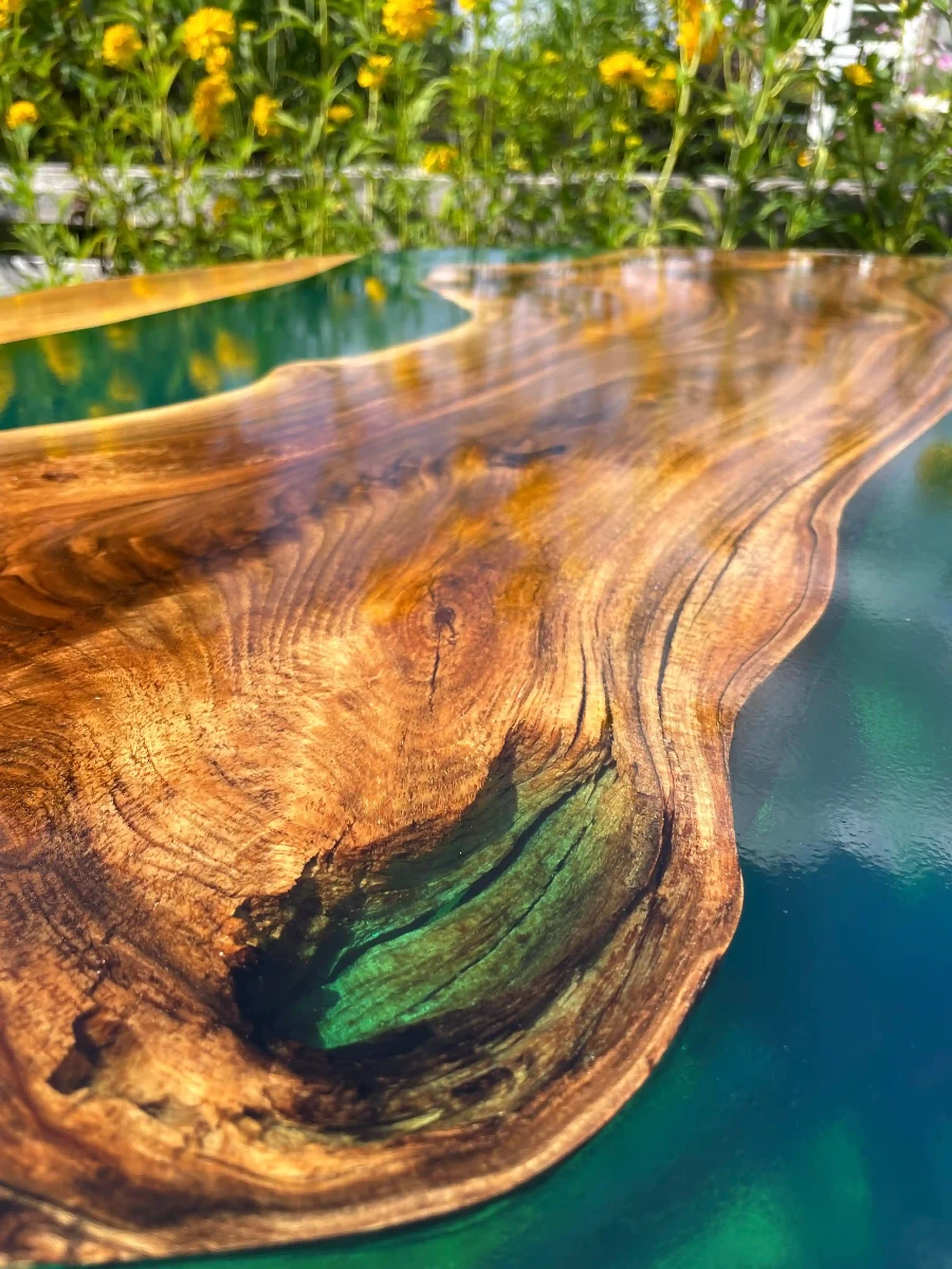 stół jadalniany z desek orzecha włoskiego w połączeniu z turkusową żywicą epoksydową na metalowych nogach zabezpieczony lakierem w połysku